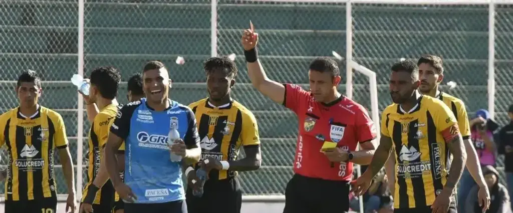El árbitro Gery Vargas le muestra la tarjeta roja al defensor de Blooming Julio Vila. 