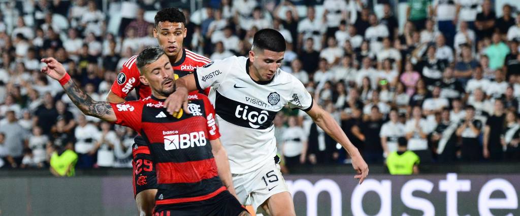  Mateo González (d) de Olimpia disputa el balón con Giorgian de Arrascaeta de Flamengo