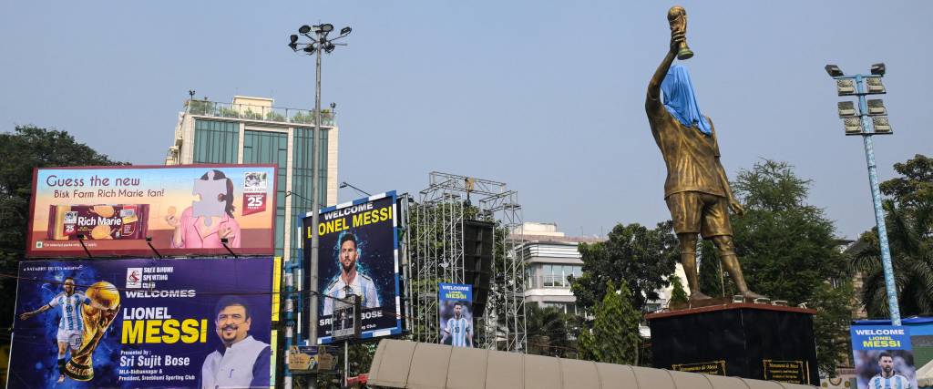 Los viajeros cruzan carteles promocionales y la estatua velada del delantero argentino número 10 del Inter de Miami, Lionel Messi, en vísperas de su visita, en Calcuta