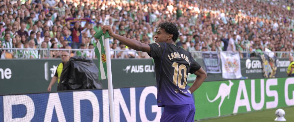 Lamine Yamal celebra su golazo posando con el banderín del córner, ante la mirada de los hinchas del Betis.