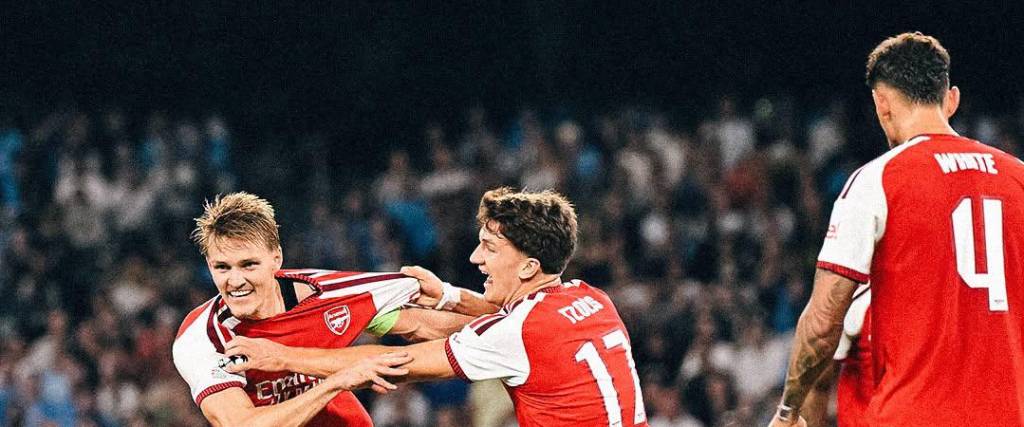 Odegaard (izq.) es sujetado por su compañero luego del primer tanto del Arsenal en Italia.