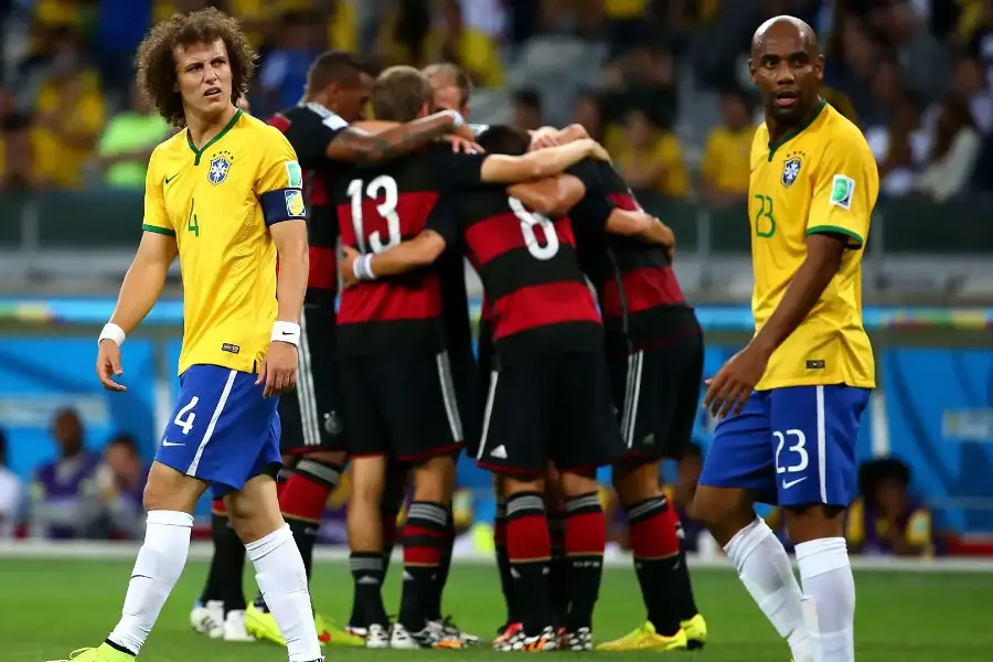 En 2014, los brasileños David Luiz (izq.) y Maicon están tristes, mientras los alemanes celebran uno de los goles. 
