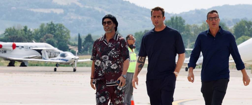 Ronaldinho (izq.) camina junto a los propietarios del club Ravenna de Italia para su presentación oficial.